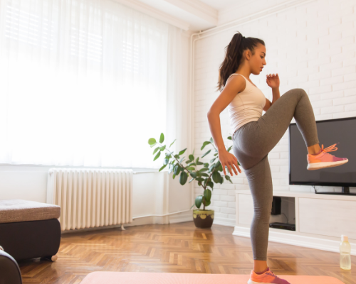 woman doing workout at home in grey leggings on pink mat in living room