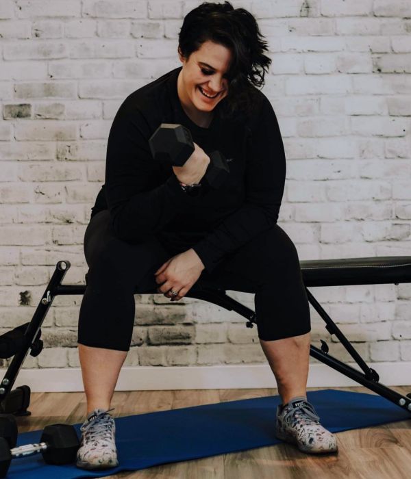 Jenna Taylor Nanaimo Personal Trainer smiling on bench doing a workout with dumbbells